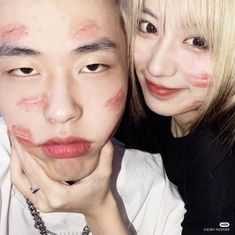 two people posing for the camera with their faces painted red and white, one woman has her chin on the other's shoulder