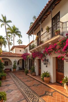 an outdoor courtyard with potted plants and flowers on the balconies, surrounded by palm trees