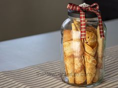 a jar filled with bread sticks sitting on top of a table next to a striped cloth