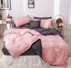 a bed with pink and grey sheets on it