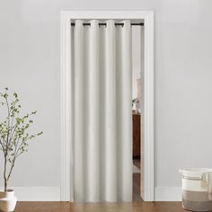 an open door with a white curtain in the middle and a potted plant next to it