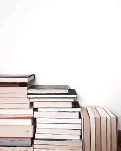 a stack of books sitting on top of a wooden floor next to a white wall