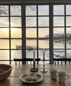 a wooden table topped with two plates of food next to a window covered in snow