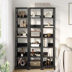 a living room filled with lots of bookshelves next to a white couch in front of a window