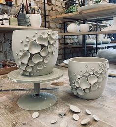 two white vases sitting on top of a wooden table