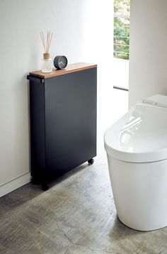 a white toilet sitting next to a black cabinet