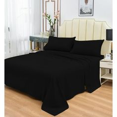 a bed with black sheets and pillows in a room