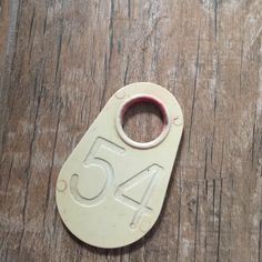 a white tag with the number fifty four on it sitting on a wooden table next to a pair of scissors