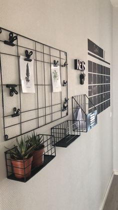 there are three black metal shelves on the wall with pictures and magnets attached to them