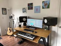 there is a desk with a keyboard, speakers and a guitar on it in the room