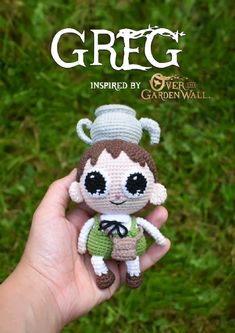 a small crocheted doll is held up in front of the camera with grass behind it