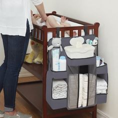 a woman standing next to a baby crib with diapers and toys in it