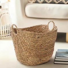 a basket sitting on top of a white table next to a book and chair in a living room