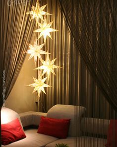 a living room filled with furniture and stars hanging from the ceiling next to a window