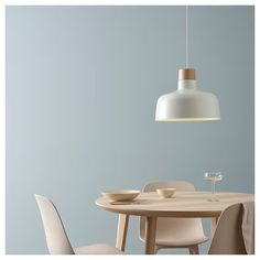 a dining room table with two chairs and a white light hanging over it, in front of a blue wall