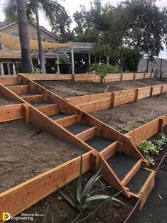 an outdoor garden with wooden steps and plants in the dirt near a house on a beach