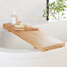 a wooden shelf sitting on top of a bath tub next to a bottle of soap