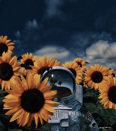 a beehive surrounded by sunflowers under a cloudy sky