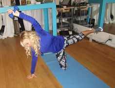 a woman doing yoga on a blue mat in the middle of a room with wooden floors