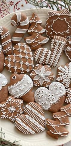 a white plate topped with lots of different kinds of gingerbread cut out in the shape of cookies