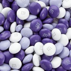 purple and white m & m's with the letter m on them are scattered together