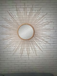 a white brick wall with a sunburst shaped mirror on it's side