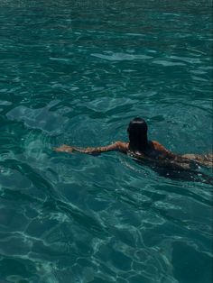 a man swimming in the ocean with his back turned to the camera and head above water