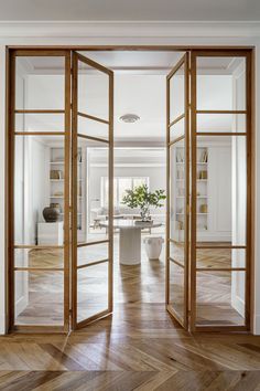 an open door leading into a living room with wood floors and white walls in the background