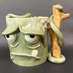 a ceramic mug with an angry face on it's side and a wooden stick sticking out of its mouth