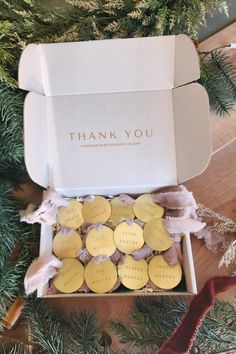 a thank you box filled with cookies on top of a wooden table next to a christmas tree