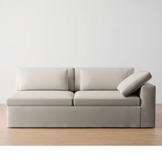 a white couch sitting on top of a hard wood floor next to a white wall