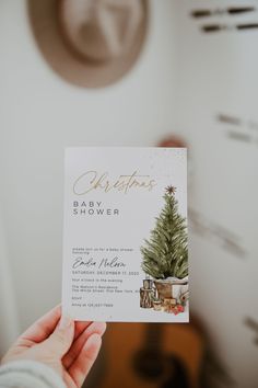 a person holding up a baby shower card with a christmas tree in the corner on it