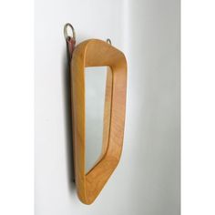 a wooden mirror hanging on the wall next to a keychain with a metal hook