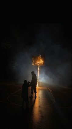 a man and child standing in the dark near a street sign with lights on it