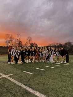 a group of people standing on top of a field next to each other in front of a cloudy sky