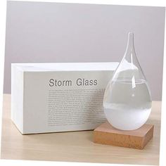 a glass vase sitting on top of a wooden block next to a box with the word storm glass in it