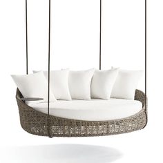 a swing bed with white pillows hanging from it's sides and two metal poles