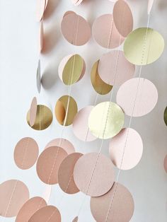 pink, gold and white paper circles hanging from strings on a wall with string attached to it