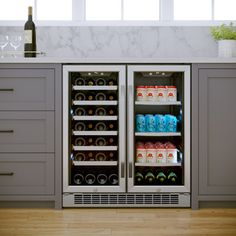 an open refrigerator with drinks in it on a wooden floor next to cabinets and drawers