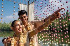 a bride and groom taking a selfie in front of flowers on the wall behind them