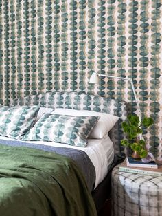 a bedroom with green and white wallpaper, a bed and two stools in front of the bed