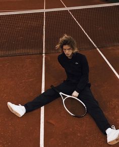 a man sitting on top of a tennis court with a racquet in his hand