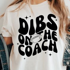 a woman wearing a t - shirt that says dubs on the coach with a football