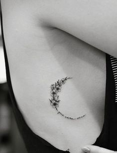 a black and white photo of a woman's stomach with a flower tattoo on it