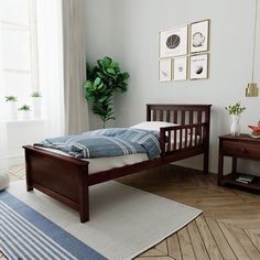 a bedroom with white walls and wood floors has a bed, two nightstands, and a potted plant in the corner