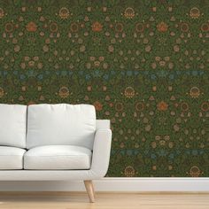 a white couch sitting in front of a wall with a green and brown pattern on it