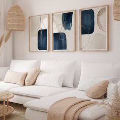 a living room filled with white furniture and paintings on the wall above it's couch