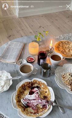 a table topped with pies and other food on top of a wooden table next to candles