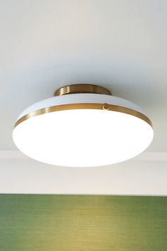 a white ceiling light hanging from the ceiling in a room with green walls and wood flooring