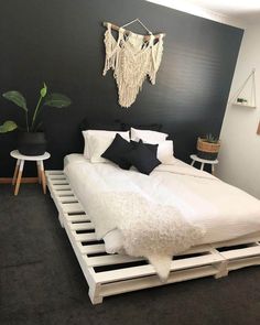 a white bed sitting in a bedroom next to a plant